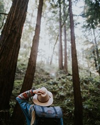 Tipps für die schönsten Touren erhalten Sie bei uns Frau mit Hut in einem Wald voll hoher Bäume