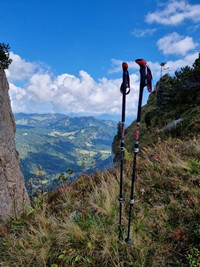 Wir verleihen hochwertige Wanderausrüstung Wanderstöcke im Boden, Ausblick ins Tal