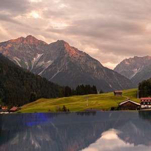 Zwischen Gipfeln im Himmel schwimmen Rooftop Infinity Pool mit Blick auf Berge, die sich im Pool spiegeln