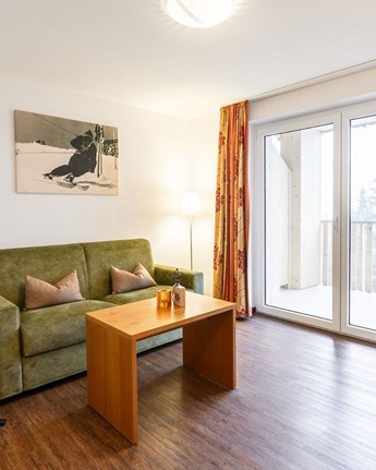 Natürliche Geborgenheit: Suite für entspannende Stunden Wohnzimmer mit Couch, Sessel & Fernseher in der Hotelsuite