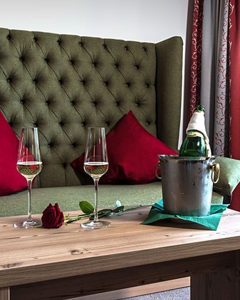 Genießen Sie eine romantische Auszeit zu zweit Couch & Couchtisch mit Sektflasche, Gläsern und einer Rose darauf