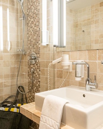 Dusche, Waschbecken und Spiegel im Hotelbadezimmer
