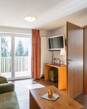 Luxuriöse Suite: Der perfekte Ort, um die Seele baumeln zu lassen Wohnzimmer mit Couch, Sessel & Fernseher in der Hotelsuite