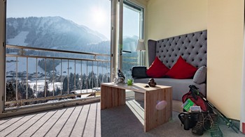 Sitzecke im Hotelzimmer vor Panoramafenster, Wanderrucksack in der Ecke