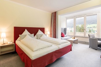 Hotelzimmer mit Doppelbett, Sitzecke und großem Fenster