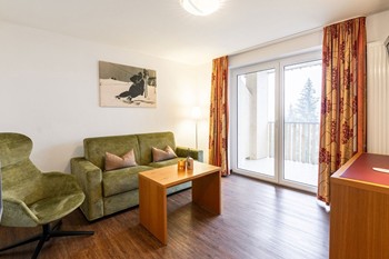 Wohnzimmer mit Couch, Sessel & Fernseher in der Hotelsuite