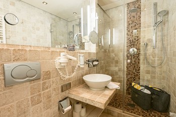 Dusche, Waschbecken und Spiegel im Hotelbadezimmer