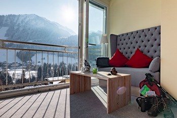 Sitzecke im Hotelzimmer vor Panoramafenster, Wanderrucksack in der Ecke