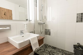 Dusche, Waschbecken und Spiegel im Hotelbadezimmer
