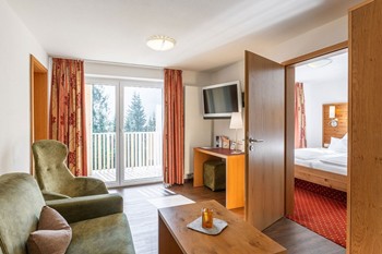 Wohnzimmer mit Couch, Sessel & Fernseher in der Hotelsuite