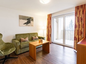 Natürliche Geborgenheit: Suite für entspannende Stunden Wohnzimmer mit Couch, Sessel & Fernseher in der Hotelsuite