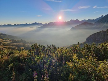 Unser Wanderhotel liegt an den Ausgangspunkten der schönsten Touren Blick auf hohe Berge und ein nebliges Tal im Sonnenschein