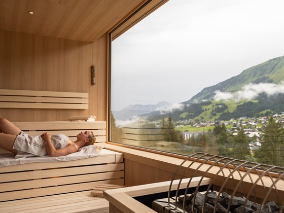 Frau liegt in einer Sauna mit Panoramafenster