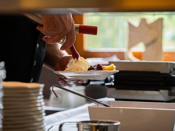 Sahne wird auf einen Teller mit Süßspeisen gesprüht