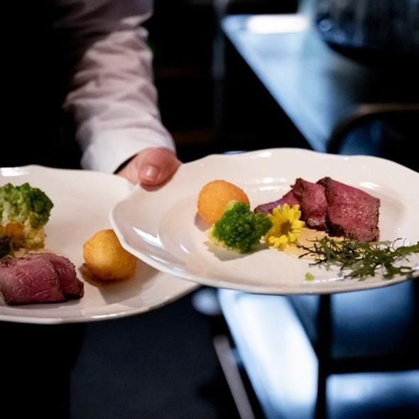 Lassen Sie sich kulinarisch verwöhnen Kellner trägt Teller mit Roastbeef und Gemüse